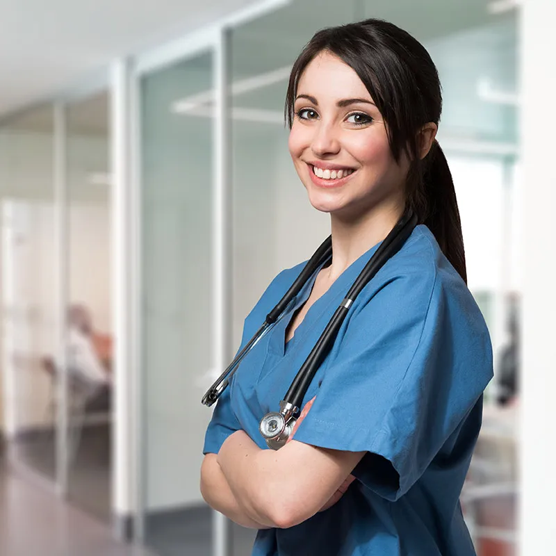 female nurse standing and smiling in hospital hallway