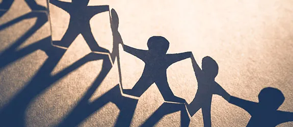 Paper cut into the shape of humans holding hands