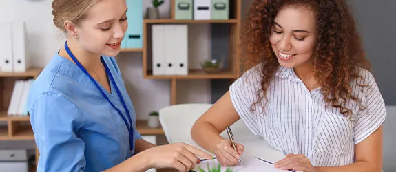 A medical assistant helps a patient fill out paperwork.