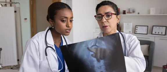 Two medical professionals look at a X-ray.