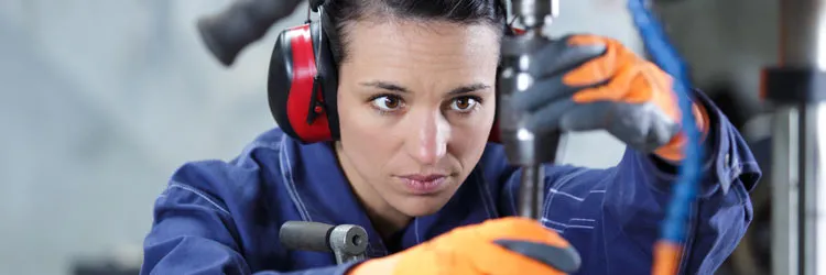 Person in protective gear operating machinery in an industrial setting.
