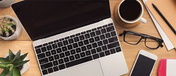 a desk with a laptop, phone and glasses