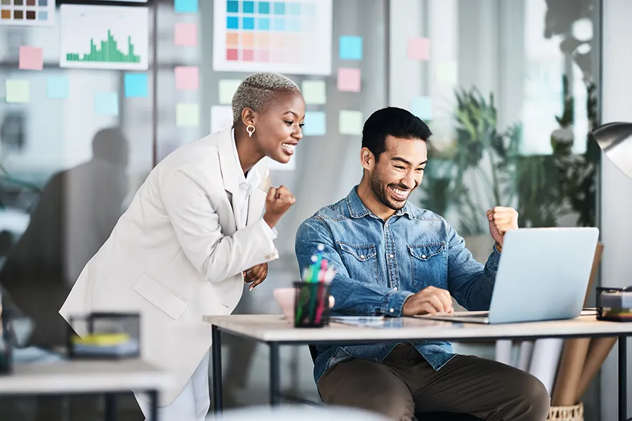 Two co-workers celebrating at a laptop