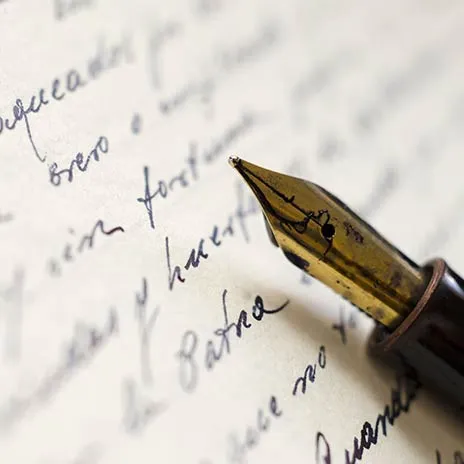 a old fashioned ink pen laying on a sheet of paper with writing on it