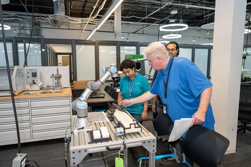 Students and instructor work with a robotic arm in the classroom