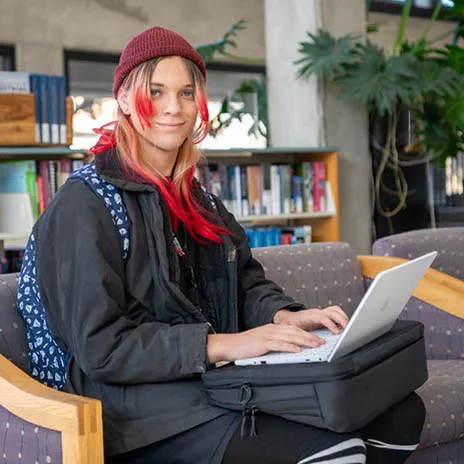 A student works on a laptop in a campus library