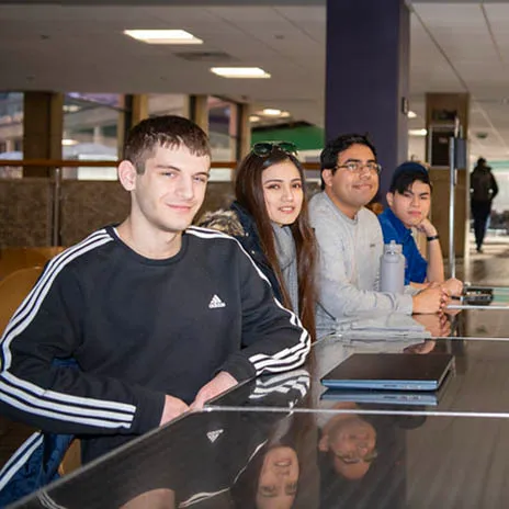 Students sit around a table in a campus library