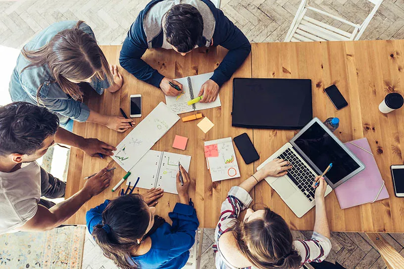 Overhead view of students working on a project together at a table