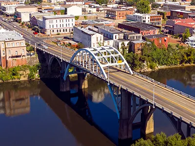 Aerial view of an arched bridge over a calm river, leading into a historic town