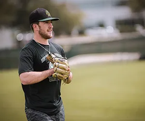 A baseball player stands in the outfield waiting for a ball with his glove