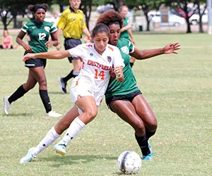 An Eastfield soccer runs alongside an opposing player while dribbling the ball down the field