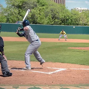 A baseball player readies their swing as a pitch is thrown