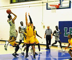 North Lake basketball player goes up for a shot with the opponents jumping to block