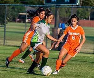 A Richland Women's Soccer player dribbles the ball past a Cedar Valley player