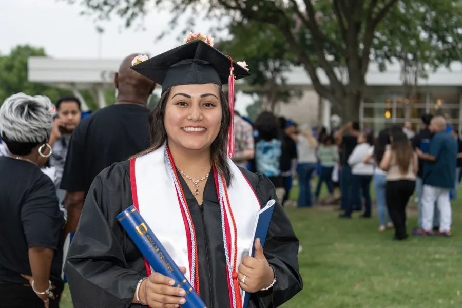 A bachelors degree graduate holds her diploma outside after the graduation ceremony