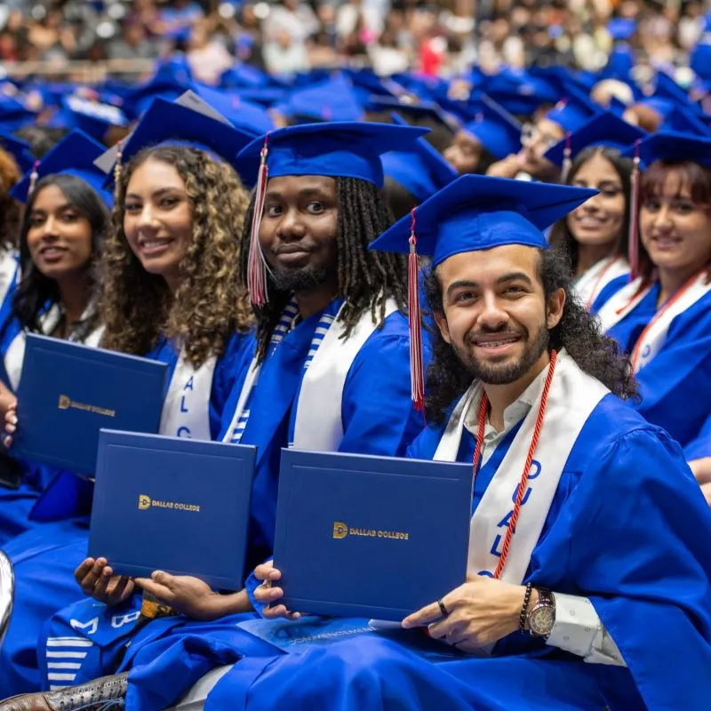 Students at graduation sit on the graduation arena floor