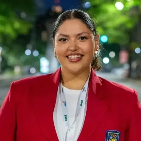 A student with a red jacket poses for a photo in a downtown setting