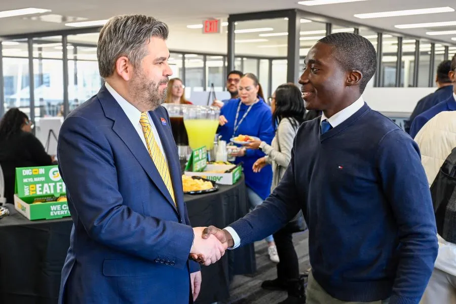 Chancellor Lonon shakes hands with a student