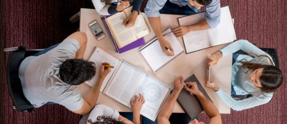 Students sit around a table, viewed from above