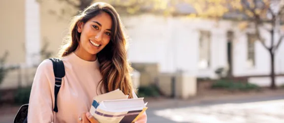 A photo of a college student holding books