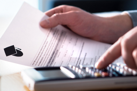 A student fills out form at a desk with a calculator nearby