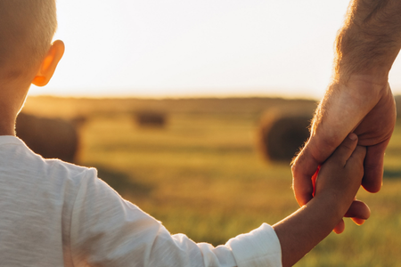 A child and parent holding hands while walking forward