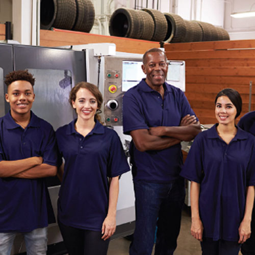 Workforce team standing in a manufacturing facility beside industrial equipment.