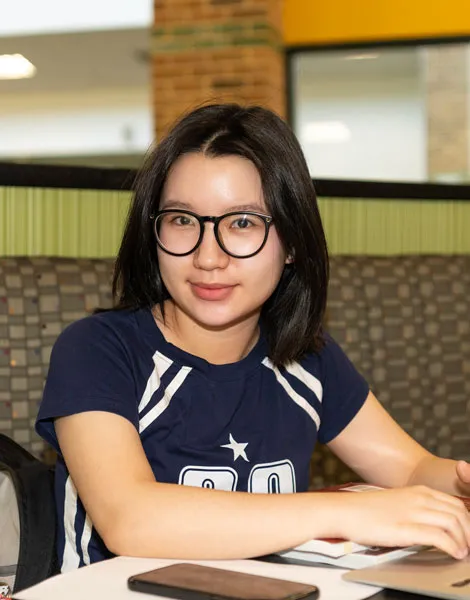 Student working on a laptop in a Dallas College common area.