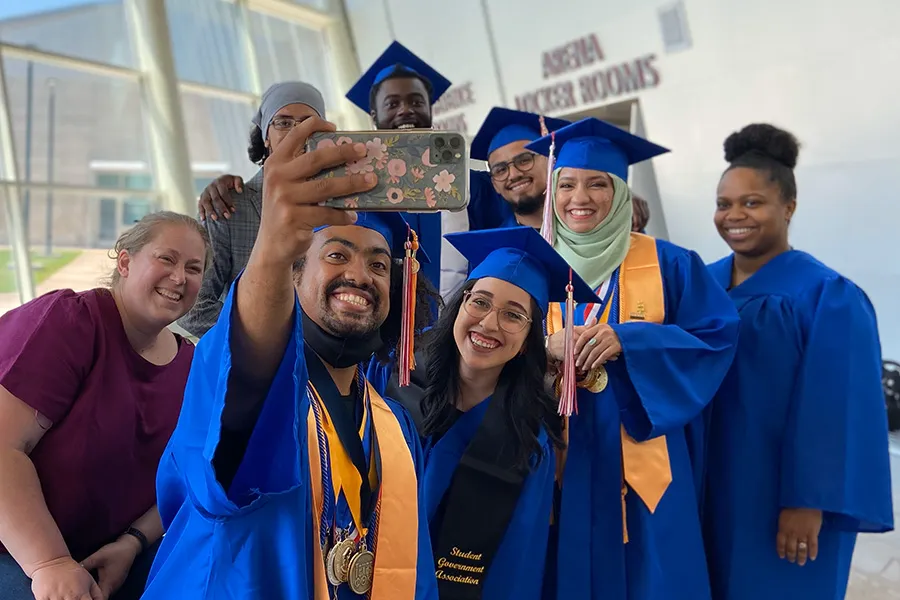 Graduates from 2023 take a group selfie before the graduation ceremony