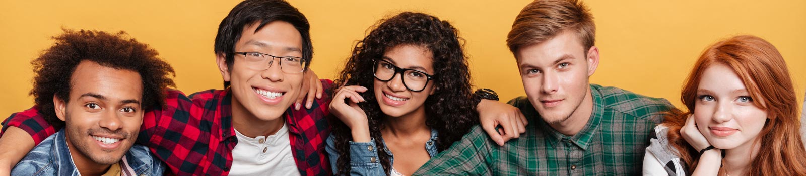 A group of five smiling friends pose against a bright yellow background