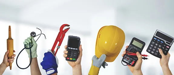 Hands raised in the air with various tools from trade jobs