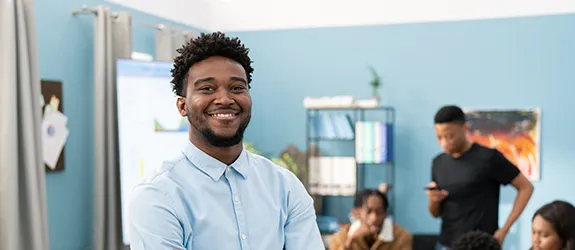 A man stands in an office while people work behind him