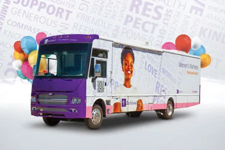 the Women's Wellness Mobile Clinic van, purple on the front and with a photo of a woman on one side