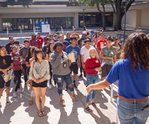 A group of students stand in the courtyard at Mountain View listening to a speaker