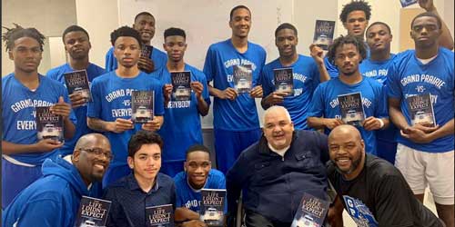 Ray Cerda poses with members of the Grand Prairie High School basketball team holding up copies of his book.