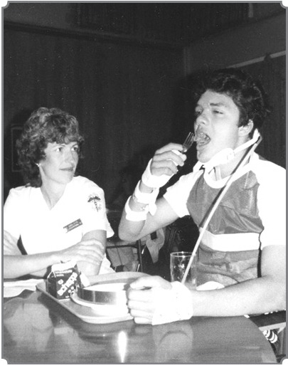 Ray Cerda sitting at table with occupational therapist learning to feed himself.