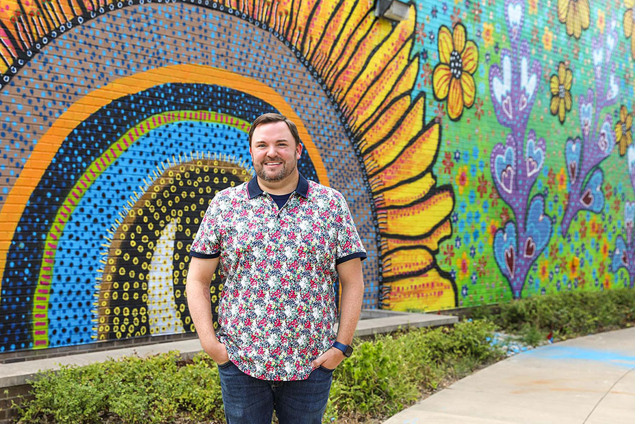 Brett Dyer standing in front of his mural