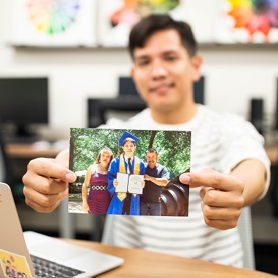 Orlando Silva holding up a photo of him and his parents at graduation.