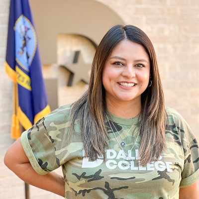 Maribel Cruz poses in front of big D with US Navy flag in the background.