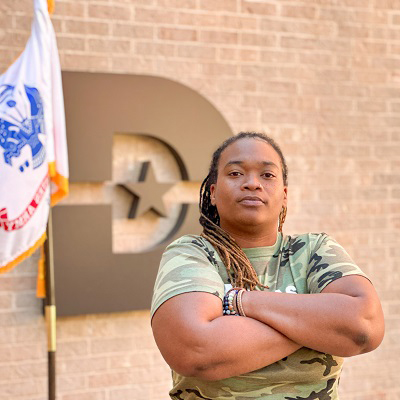 Deandrea Montague posing in front of the big D with a US Army flag in the background.