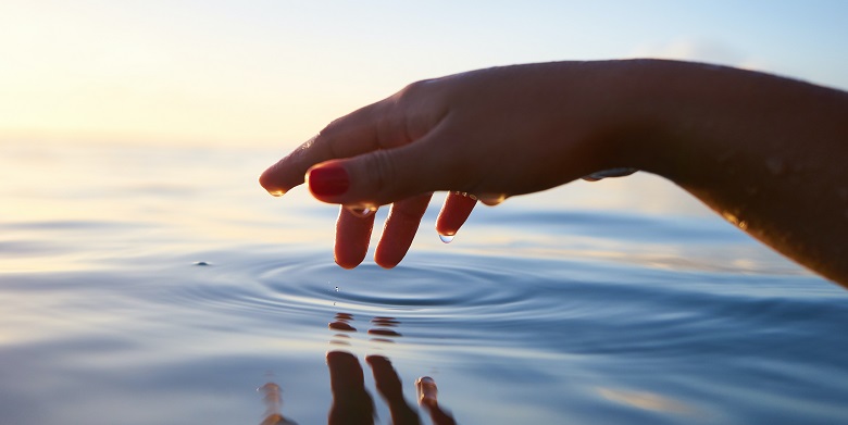 Decorative image of hand touching still water.
