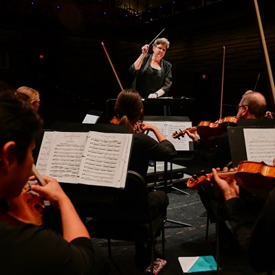 View from back of orchestra with Kathryn Brownlee conducting.