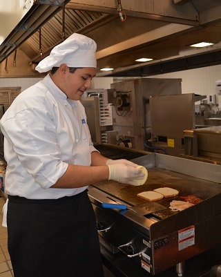 Daniel Alvarenga using stove to toast bread for sandwich.