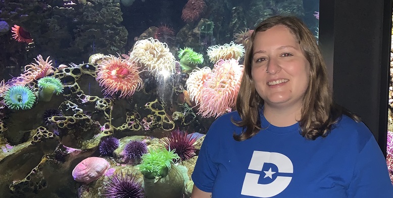 Nina Nahvi standing in front of an aquarium.