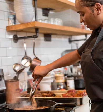 Temika McCaskill tending meat in a frying pan.