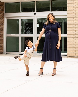 Rubia Laurentino standing in front of campus building. and holding her son's hand
