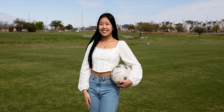 Paris Sithavong standing on soccer field holding a soccer ball.