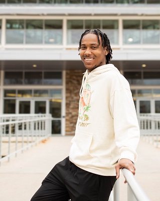 Xavier Chancellor leans on railing in front of campus building.