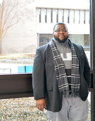 Brian Daniels standing in front of a window on campus.
