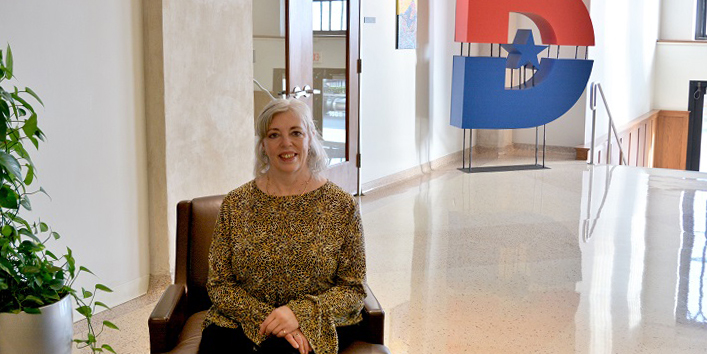 Georgia Alvarez sitting in entrance to Dallas College.